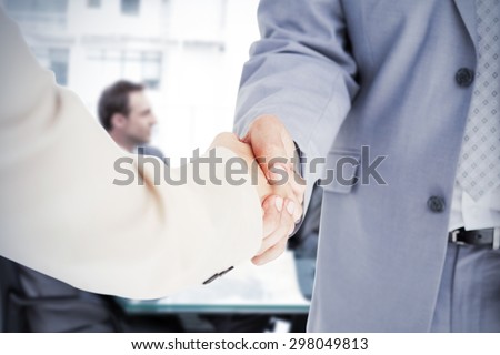 People in suit shaking hands against thoughtful businesswoman talking to her team during a meeting