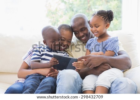 Happy family on the couch using digital tablet in the living room