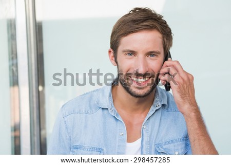Happy man smiling at the camera while telephoning