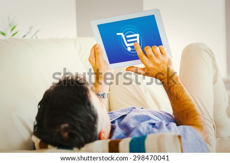Man laying on sofa using a tablet pc against trolley