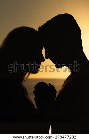 sunset of a beautiful day against silhouette of affectionate couple face to face holding hands