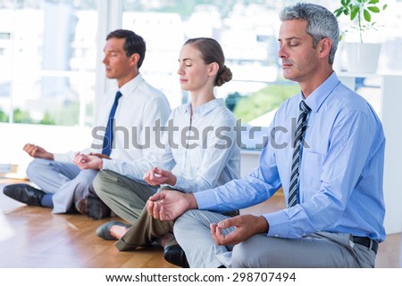 Business people doing yoga on floor in office