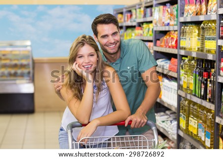 Portrait of smiling bright couple buying food products at supermarket