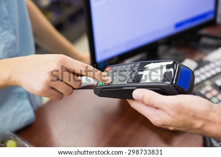 Woman at cash register paying with credit card in supermarket