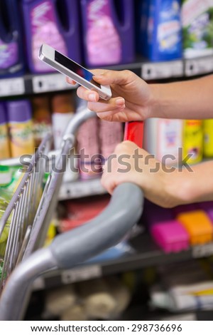 woman buy products and using his smartphone at supermarket
