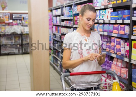 Woman buy products and texting at supermarket