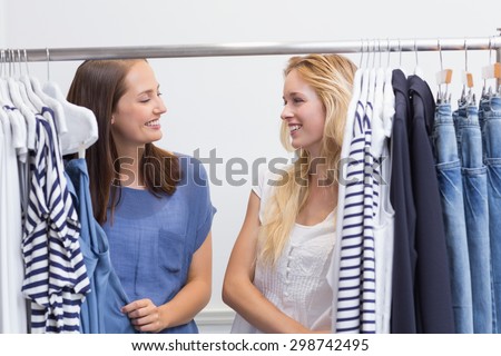 Two happy friends browsing in the clothes rack