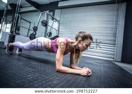 Side view of a muscular woman on a plank position