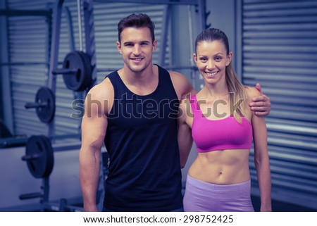 Portrait of a smiling muscular couple with arms around