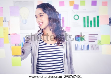 Pretty designer looking at post its on window in the office