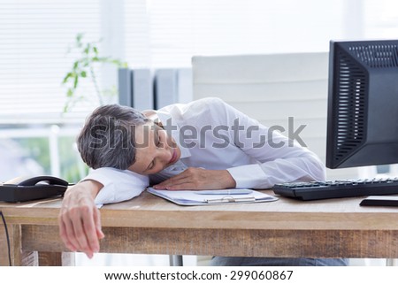 Tired businesswoman sleeping at her desk in her office