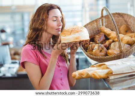 Pretty brunette smelling loaf of bread at the bakery