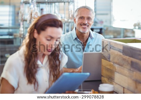 Happy man looking at camera and using laptop in the bakery store