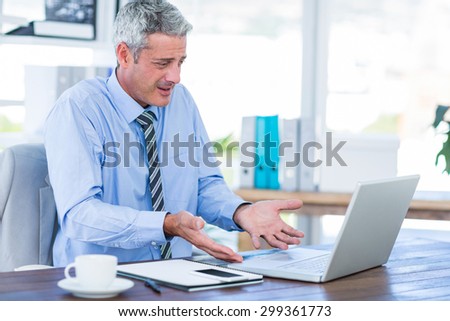 Confused businessman looking at laptop computer in office