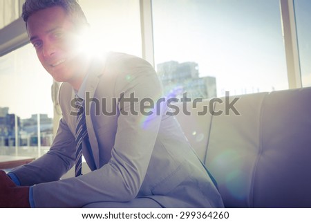 Happy business man sitting on sofa and looking at camera in living room