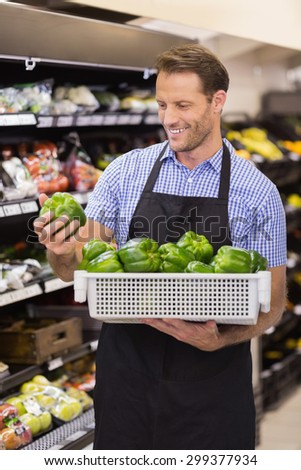 Smiling handsome worker taking a box with vegetables in supermarket