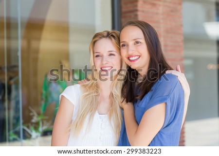 Smiling girl friends with arms around looking away