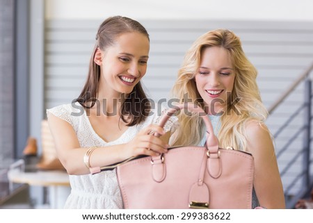 Two happy women looking at handbag in shopping mall