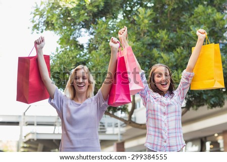 Smiling women friends holding shopping bags outside