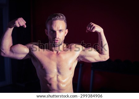 Muscular man flexing his biceps on a shadow background