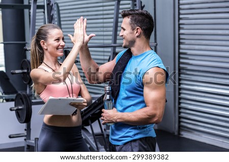 Female coach giving high five with a muscular man