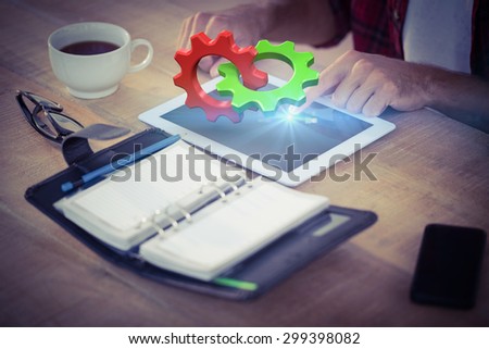 Green and red cog and wheel against creative businessman using a tablet