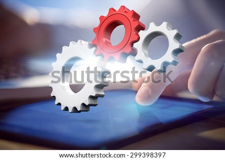 White and red cogs and wheels against businessman using laptop and tablet at desk