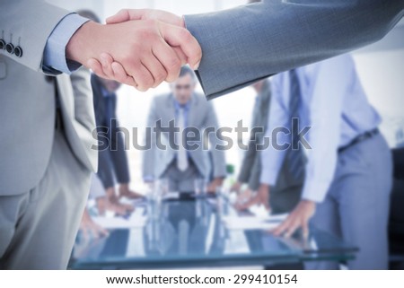 Business handshake against business colleagues discussing about work