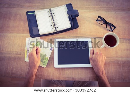 Money bundle and digital tablet on a wood table
