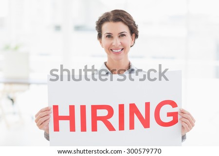 Businesswoman holding sign in front of her in an office