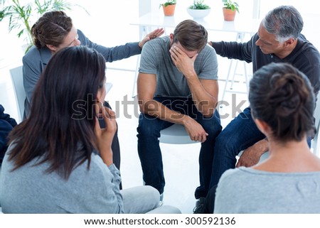 Concerned patients comforting another in rehab group at a therapy session