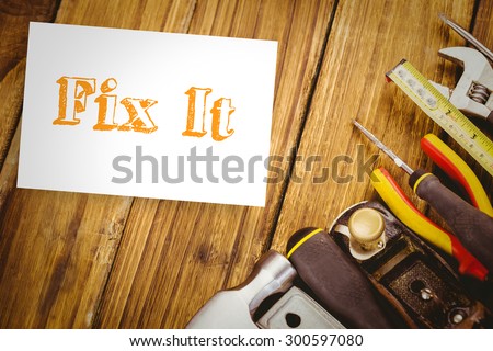 The word fix it and white card against desk with tools