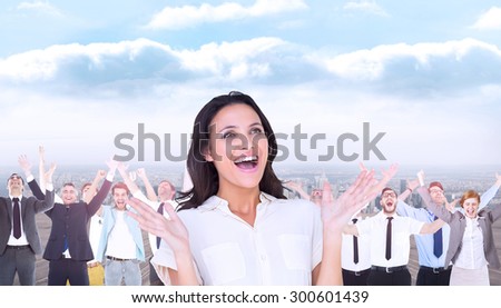 Surprised brunette with hands up against balcony overlooking city