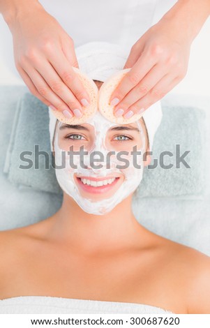 Upward view of hands cleaning woman face with cotton swabs at spa center