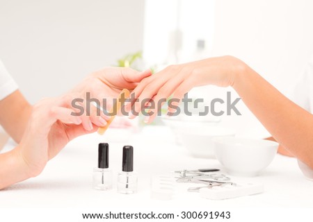 Close up of beautician filing female clients nails at spa beauty salon