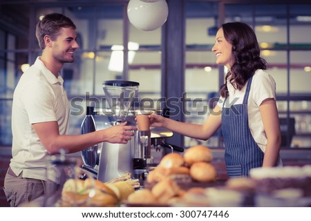 Pretty smiling barista serving a customer at the coffee shop