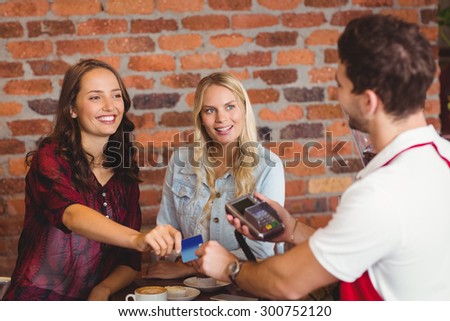 Pretty friends handing a credit card at the coffee shop