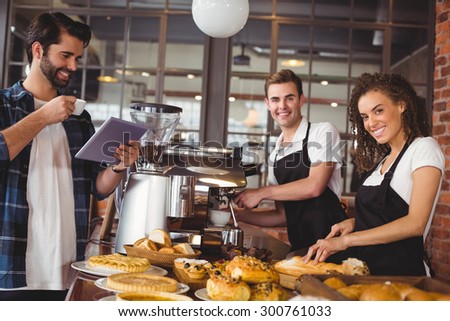 Portrait of smiling colleagues serving customer with tablet and coffee at coffee shop