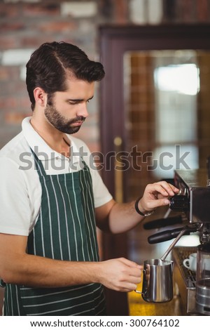 Barista steaming milk at the coffee machine at the coffee shop