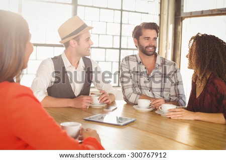 Smiling friends talking and having coffee together at coffee shop