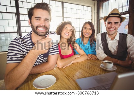 Portrait of smiling friends enjoying coffee together at coffee shop