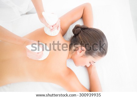 Beautiful brunette enjoying a herbal compress massage at the health spa