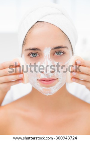 Upward view of hands cleaning woman face with sponge at spa center