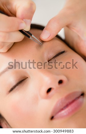 Close up view of woman using tweezers on patient eyebrow at the health spa