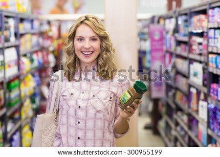 Portrait ofa happy smiling blonde womanhaving a product in her hands in supermarket