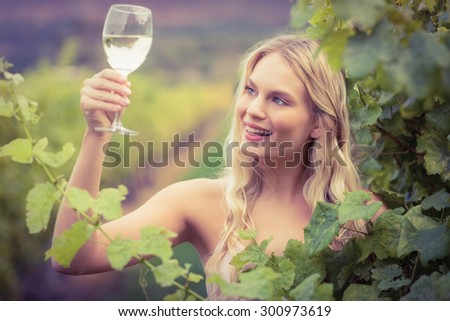 Young happy woman holding a glass of wine in the grape fields