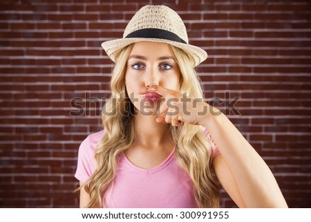 A beautiful hipster having a fake mustache against a brick wall