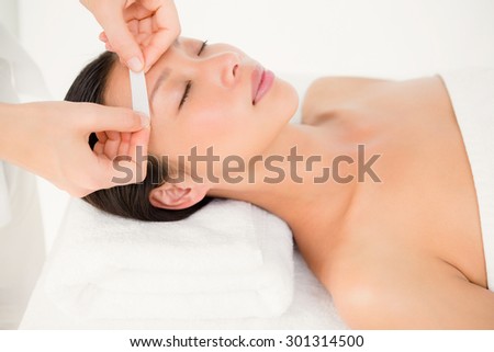 Close up view of hands waxing beautiful womans eyebrow