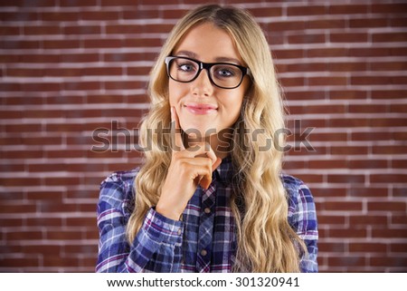 Portrait of gorgeous smiling blonde hipster thinking against red brick background