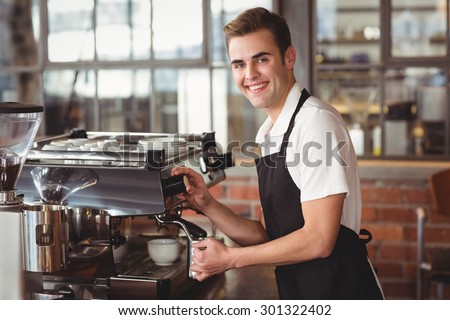 Portrait of smiling barista steaming milk at coffee machine at coffee shop